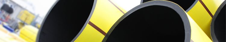 Close-up of large, yellow industrial pipes with black interiors, arranged at an angle. The background is blurred, suggesting an outdoor setting.