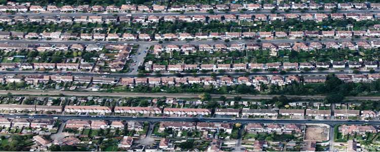 Aerial view of a residential neighborhood with rows of houses, streets, and green spaces arranged in a grid pattern.
