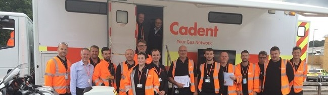 Cadent team members in high-visibility jackets standing beside a company vehicle and motorcycle.