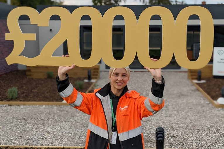 A person wearing an orange construction jacket holds up a large gold-colored 