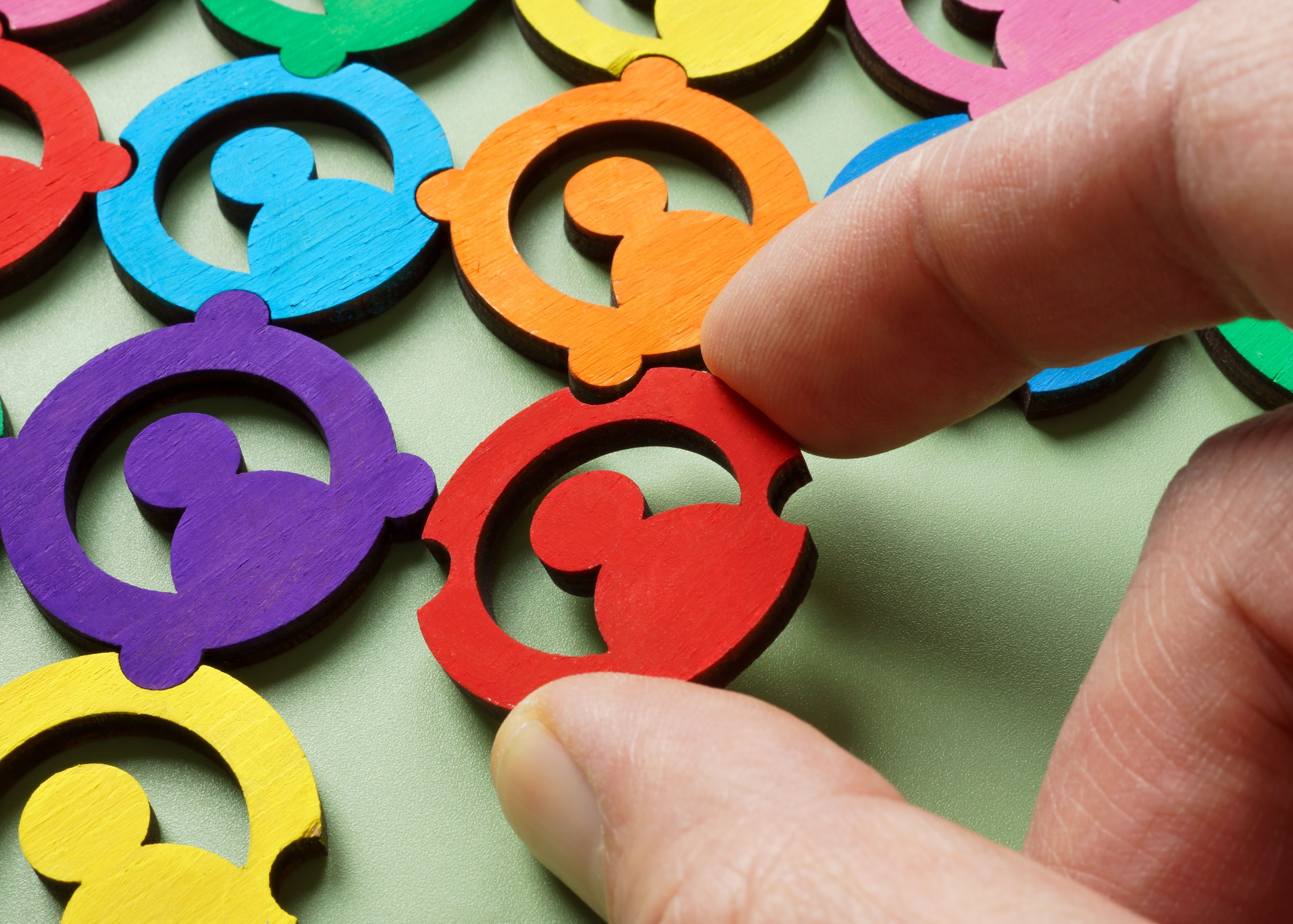 A hand adding a piece to a colourful puzzle. Diversity and team collaboration