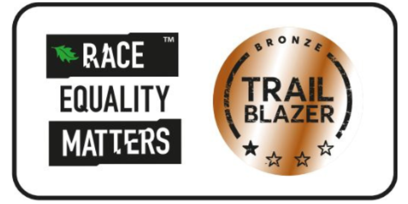 Race Equality Matters logo alongside a bronze circular badge labeled ‘Trailblazer,’ decorated with stars around the bottom.
