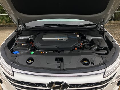 The image shows the engine compartment of a Hyundai car with the hood open. Visible are the clean, orderly components of a modern engine with the Hyundai logo.