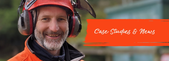 Smiling man in orange safety gear and earmuffs stands outdoors, conveying warmth and professionalism. Red banner reads Case Studies & News.