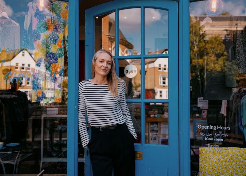 Portrait of a confident, mature female shop owner standing in the doorway of their small shop