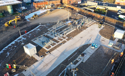 Aerial view of an industrial site with equipment, fenced areas, and construction vehicles on a cleared plot of land.