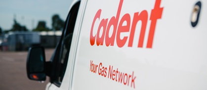 Close-up of a white van displaying the branding 'Cadent Your Gas Network' in red letters. The background shows a blurred outdoor setting.